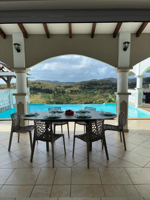 a table and chairs with a view of a pool at Villa Dulce Caliente au Vauclin in Le Vauclin