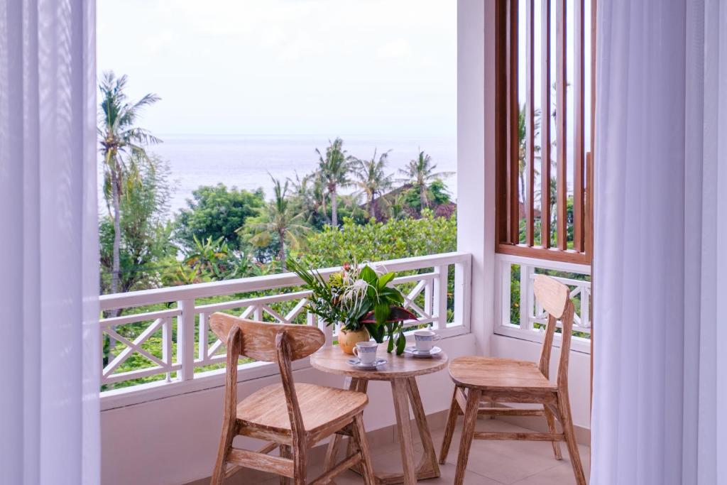 a balcony with a table and chairs and a view of the ocean at Bukit Adi in Amed