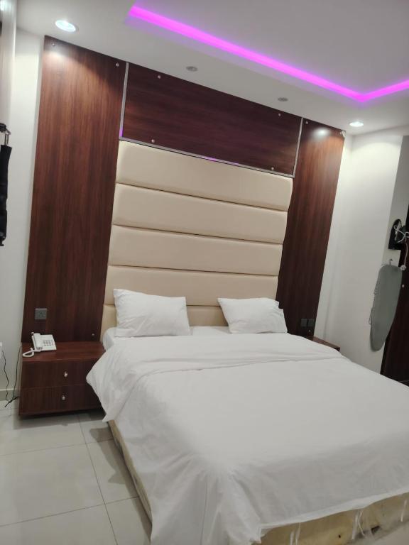 ein Schlafzimmer mit einem großen weißen Bett mit violettem Licht in der Unterkunft ميلاف للشقق المخدومة Milaf For Serviced Apartments in Al Shafa