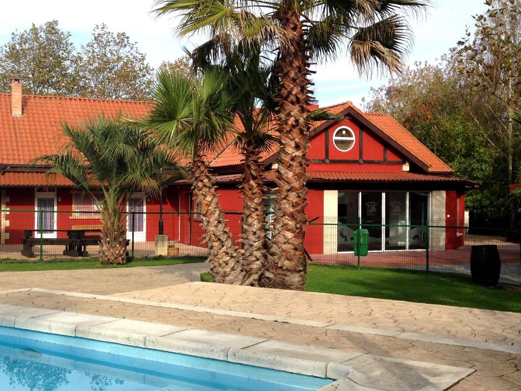 una casa roja con palmeras y piscina en Hostel albergue Paradiso en Hinojedo