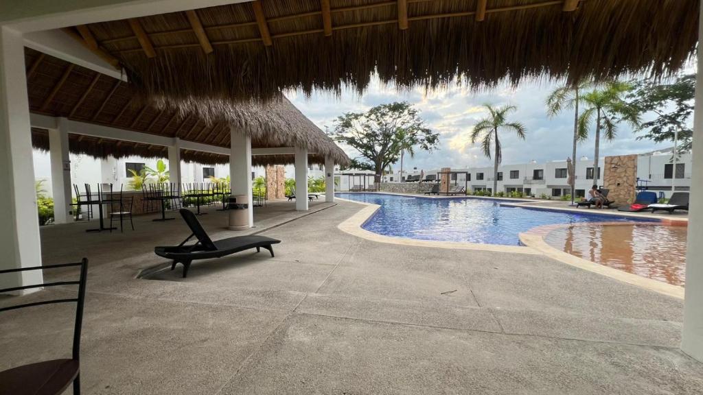 a resort swimming pool with a chair and a straw umbrella at Casa Parota in Naranjo