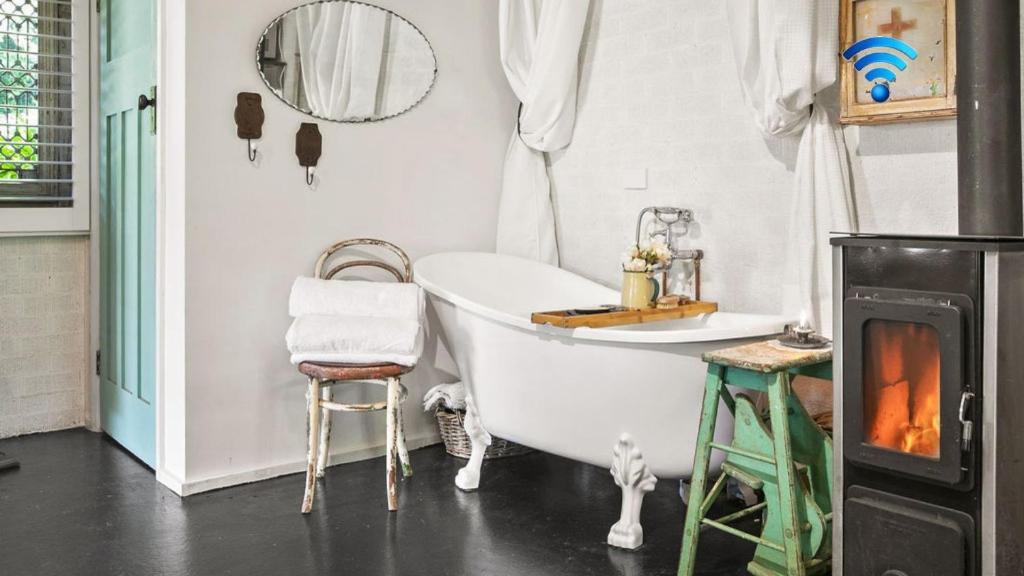 a bathroom with a bath tub and a stove at Saint Eloi Le Studio in Bowral
