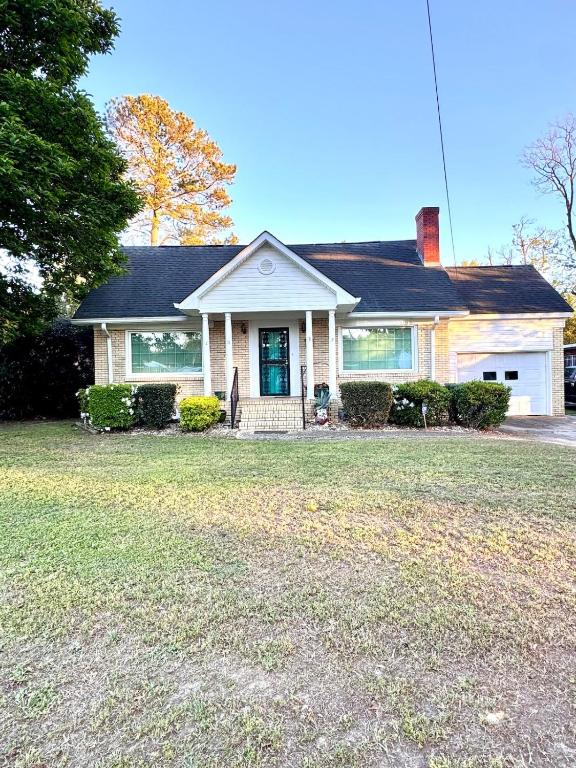 a white house with a green door on a yard at The Tee Time Cottage in Augusta