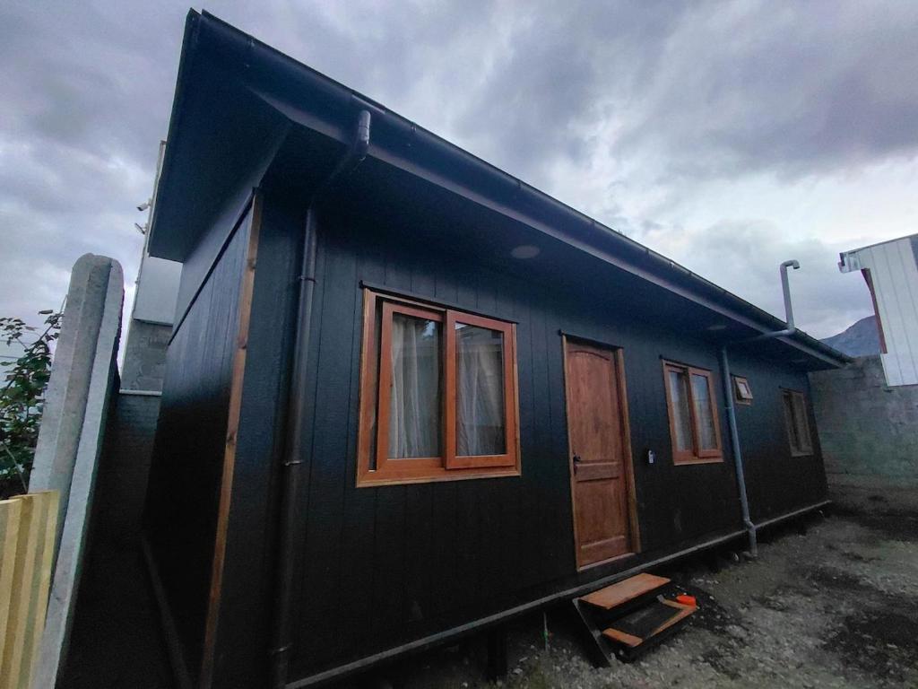 a black house with wooden doors and windows at Siloe in Coihaique