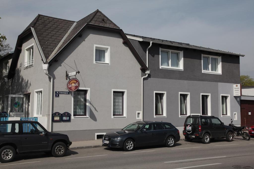 dos coches estacionados frente a un edificio en Pension Casa Topolino, en Wiener Neustadt