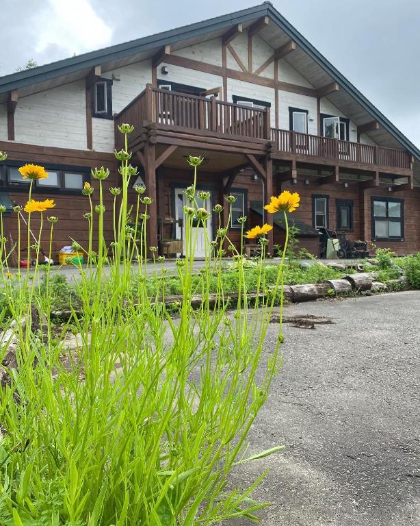 a house with a balcony and flowers in front of it at Yubari Forest Farm BandB in Yubari