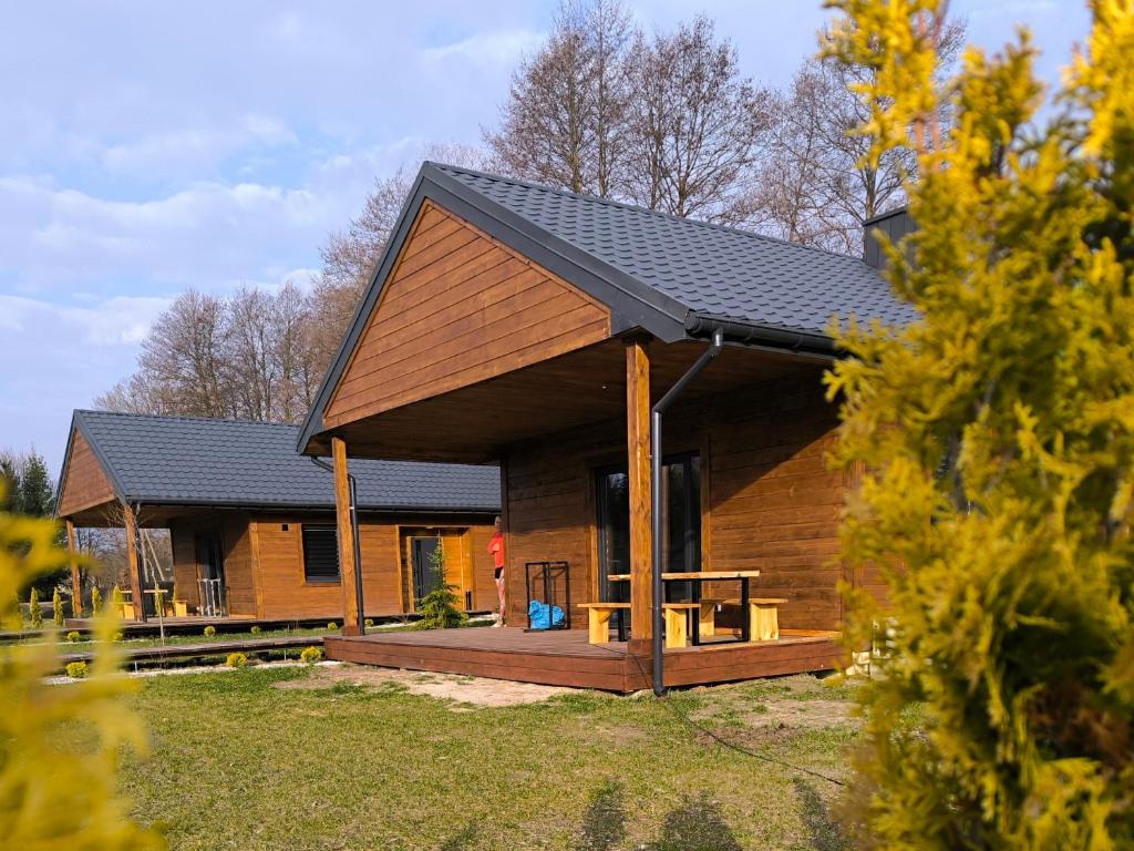 a large wooden cabin with a porch and a deck at Azyl na Polesiu domki przy Poleskim Parku Narodowym in Załucze Nowe