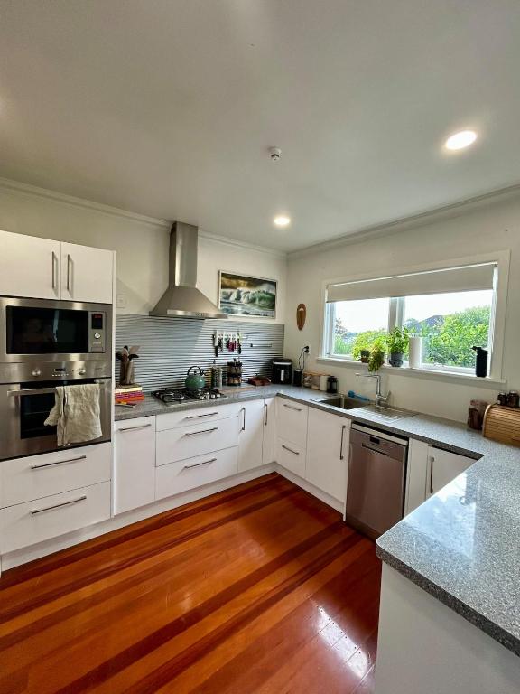 a kitchen with white cabinets and a large window at Sunbeam Cottage in Havelock North