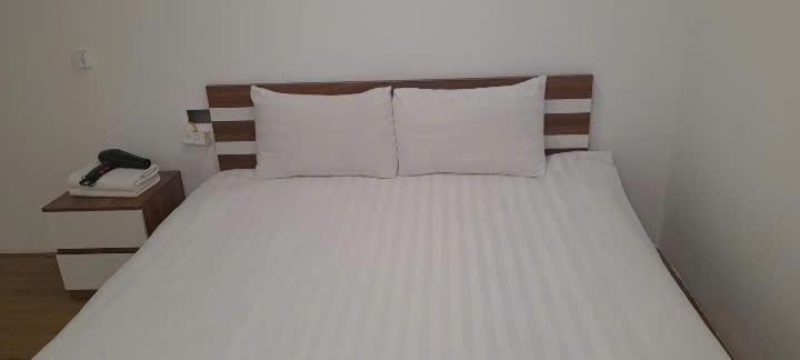 a bed with white pillows and a phone on a table at Green Nest Hotel in Hanoi