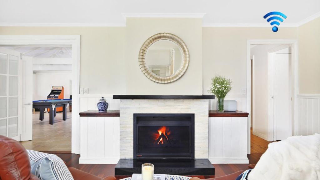 a living room with a fireplace and a mirror at Southrose Cottage in Moss Vale