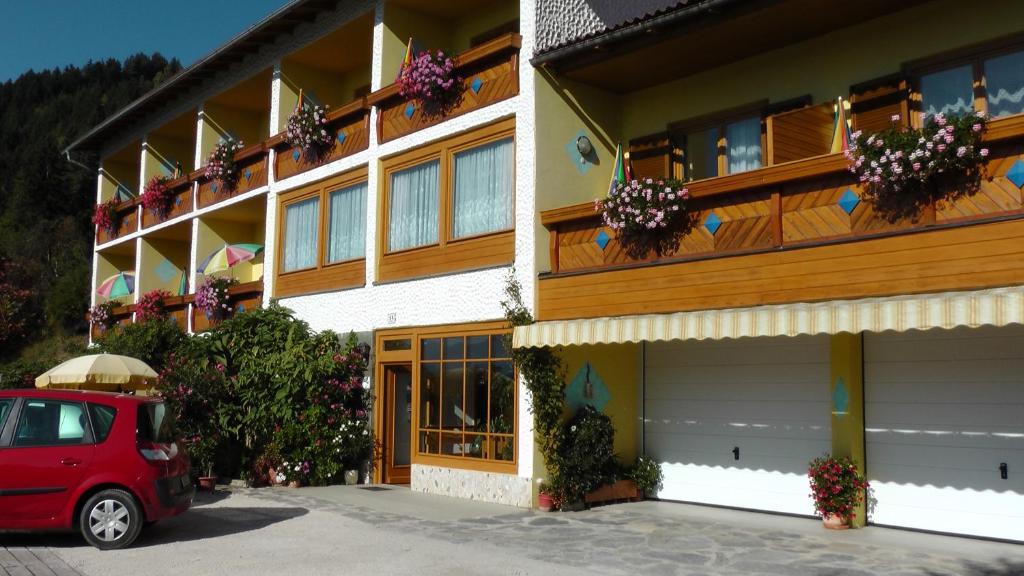 a red car parked in front of a building at Pension zum Mühlrad in Millstatt