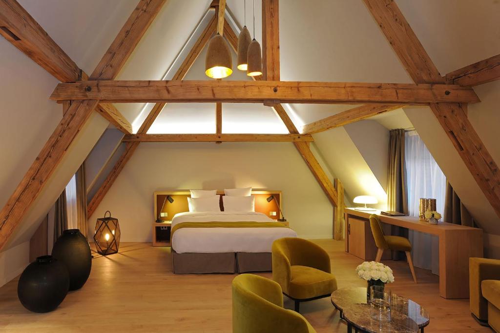 een slaapkamer met een bed en stoelen in een kamer bij 5 Terres Hôtel & Spa Barr - MGallery Hotel Collection in Barr