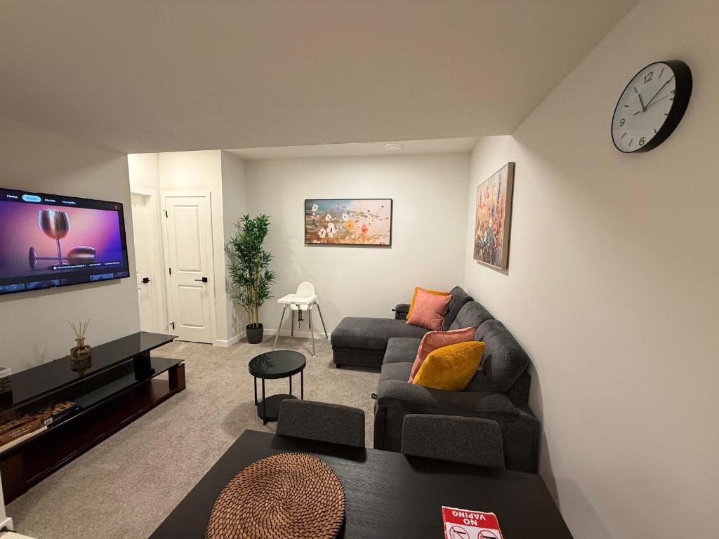 a living room with a couch and a clock on the wall at Modern Comfort in Calgary