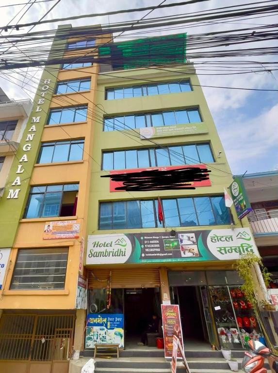 a tall yellow building with a sign on it at Hotel Sambridhi in Panepa