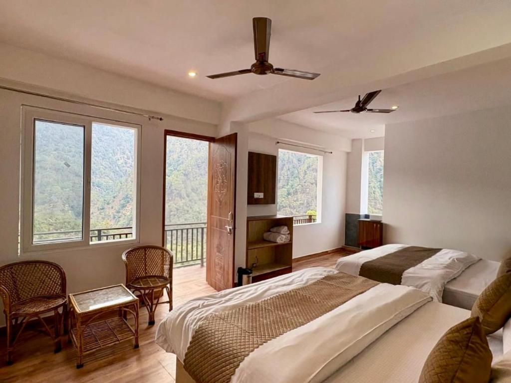 a hotel room with two beds and a balcony at Hotel Kedarkhand in Sonprayag