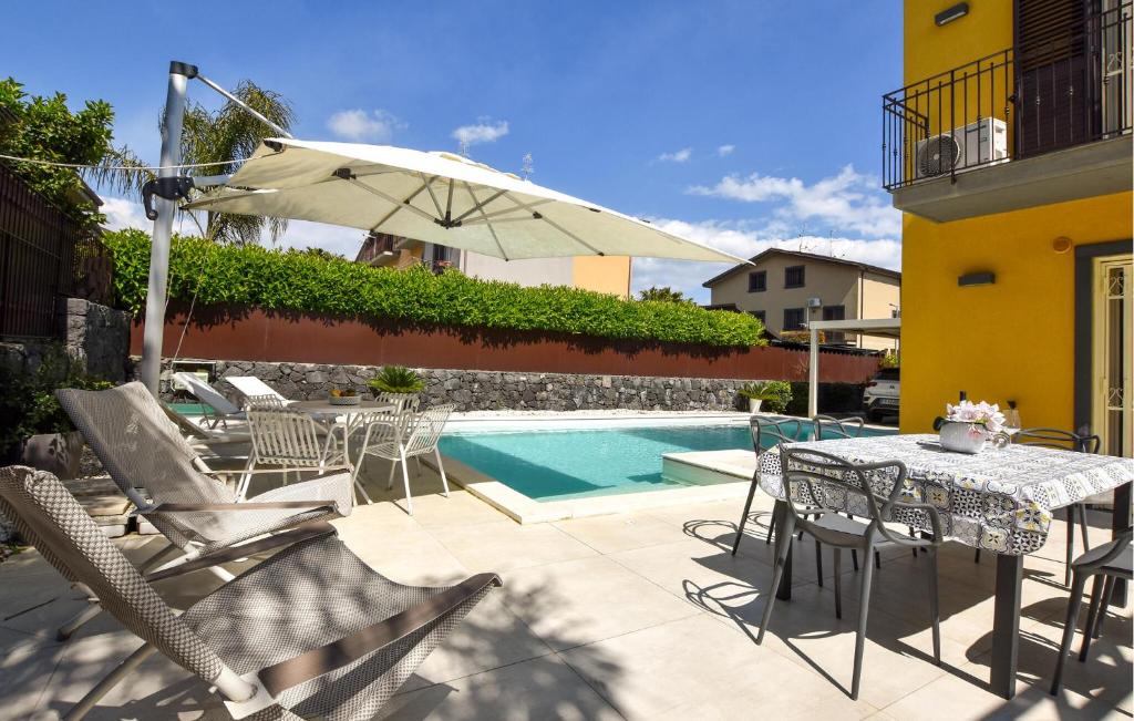 a patio with a table and chairs and an umbrella at Maison De Paris in San Giovanni la Punta