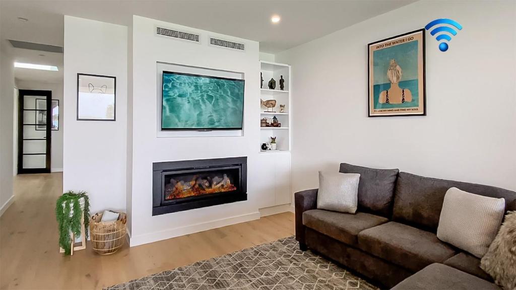 a living room with a couch and a fireplace at Luxe by the Lake in Lake Illawarra