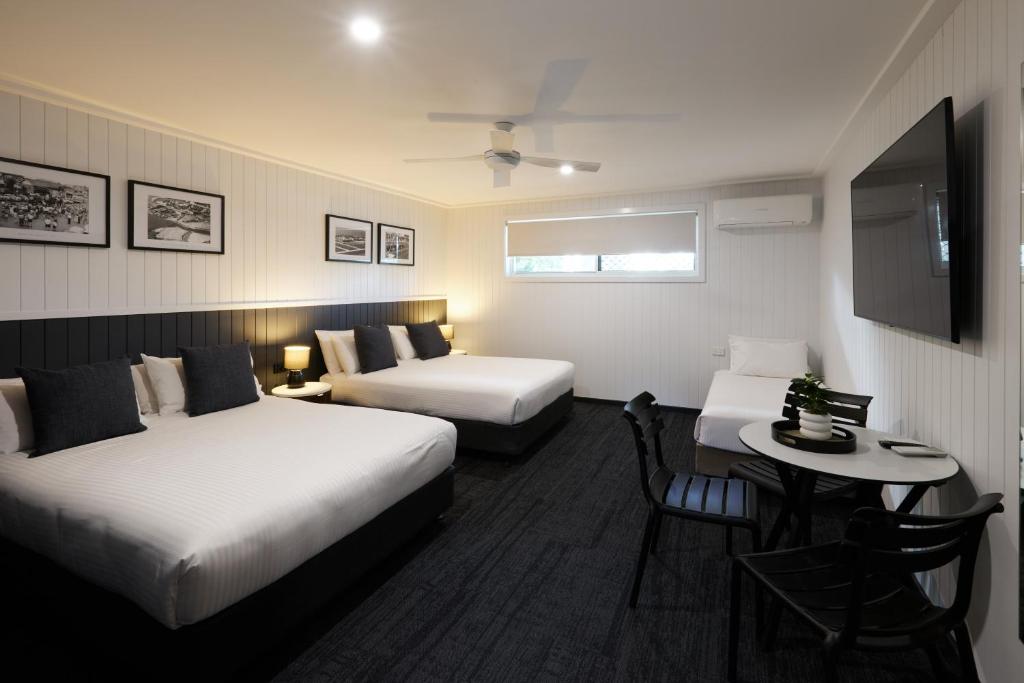 a hotel room with two beds and a table at Settlers Inn in Port Macquarie