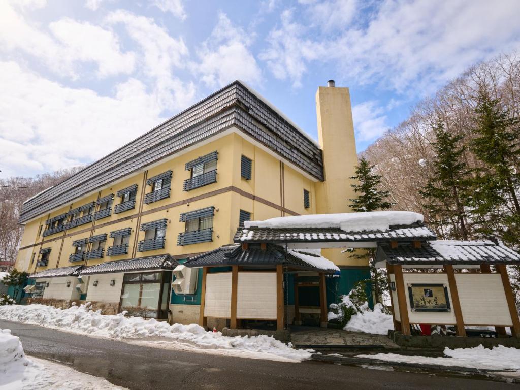 a large yellow building with snow on the ground at Oyado Kiyomizuya in Noboribetsu