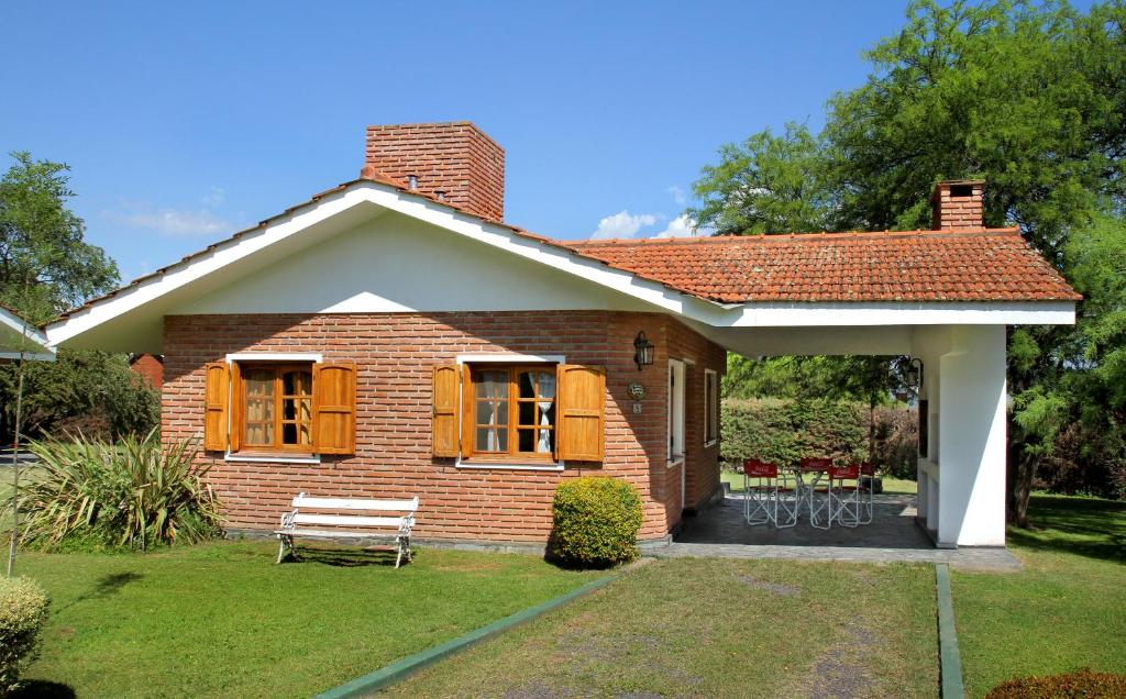 une petite maison en briques avec un banc dans la cour dans l'établissement Cabañas y Lofts El Portal, à Villa General Belgrano