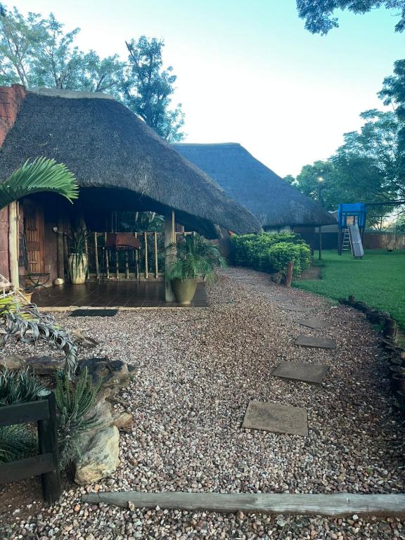a building with a thatched roof with a gravel yard at Lapa Lê Lê Lodge in Ellisras