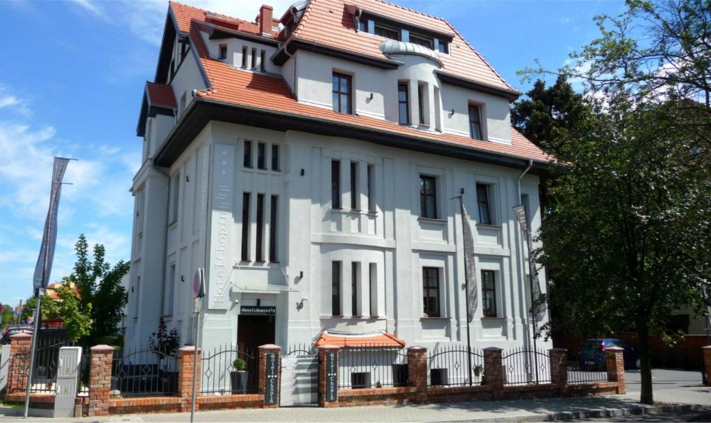 een groot wit huis met een rood dak bij Hotel Chopin Bydgoszcz in Bydgoszcz