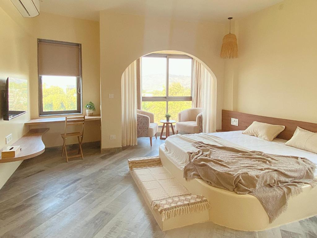 a bedroom with a large bed and a desk and window at Zumi Stays in Udaipur