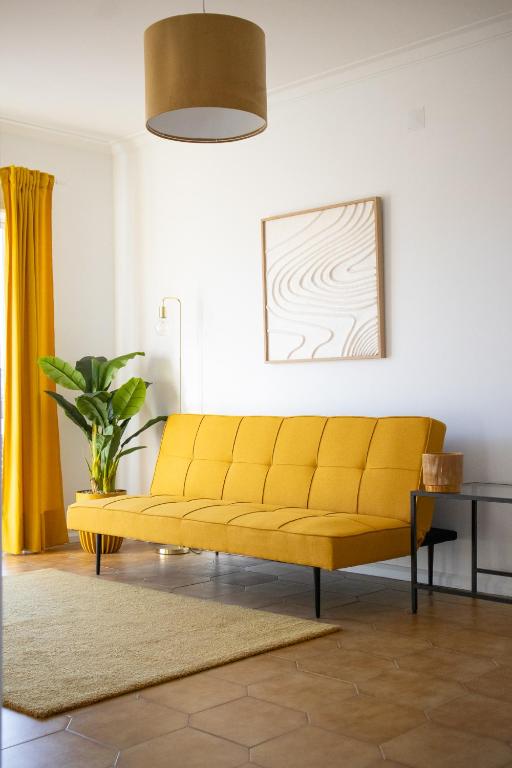 a yellow couch in a living room with a table at Bombarda 51 - Inn & Hostel in Vila Praia de Âncora