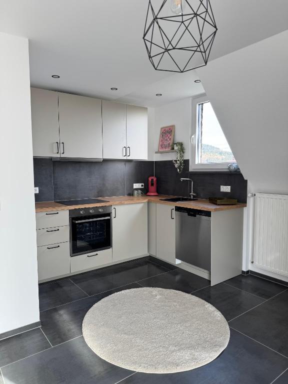 a kitchen with white cabinets and a rug on the floor at Ferienwohnung Eifelhirsch in Ettringen