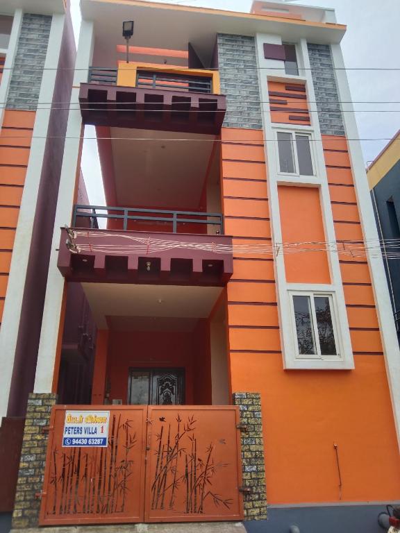 an orange house with a balcony and a gate at Peter's villa in Kuttālam