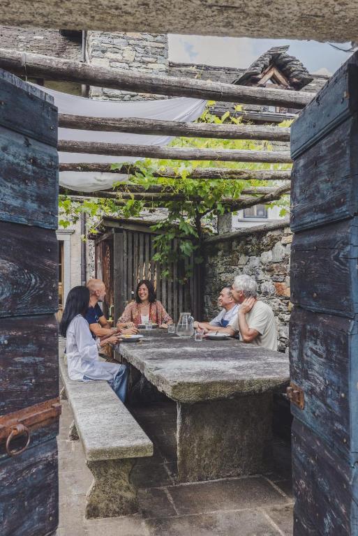 a group of people sitting at a stone table at Ecovillage Sanctuary Bordei in Palagnedra