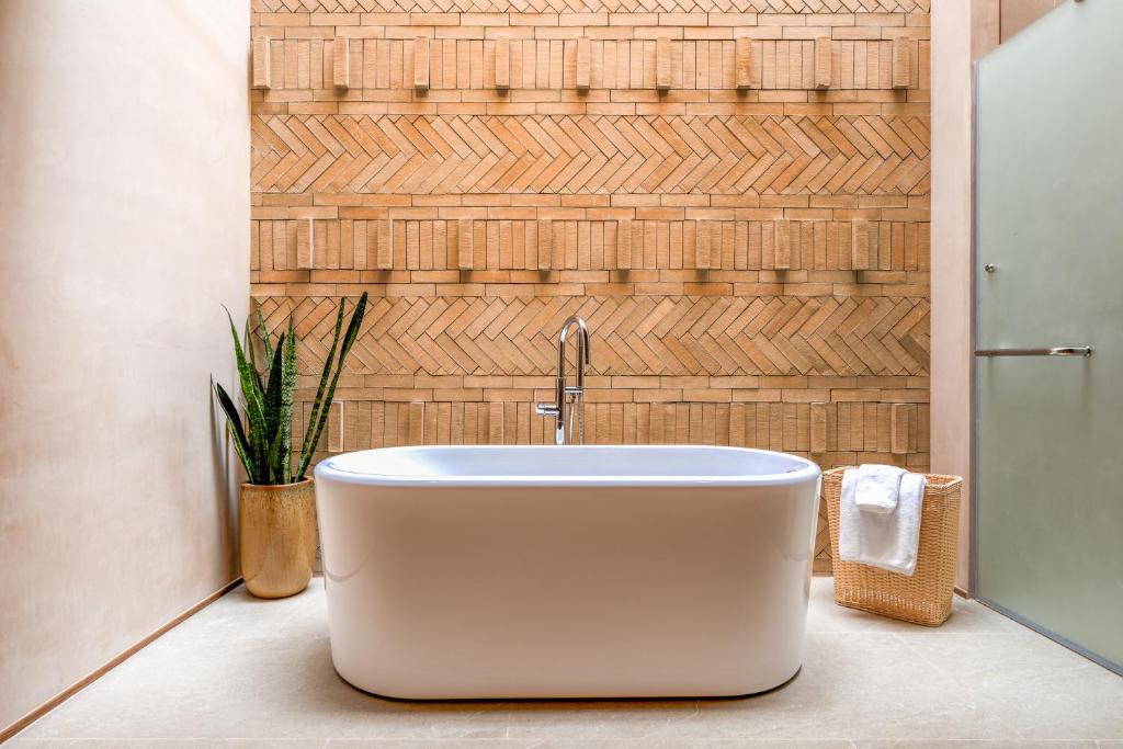 a white bath tub in a bathroom with a wall at Peace House Koh Phi Phi in Phi Phi Islands