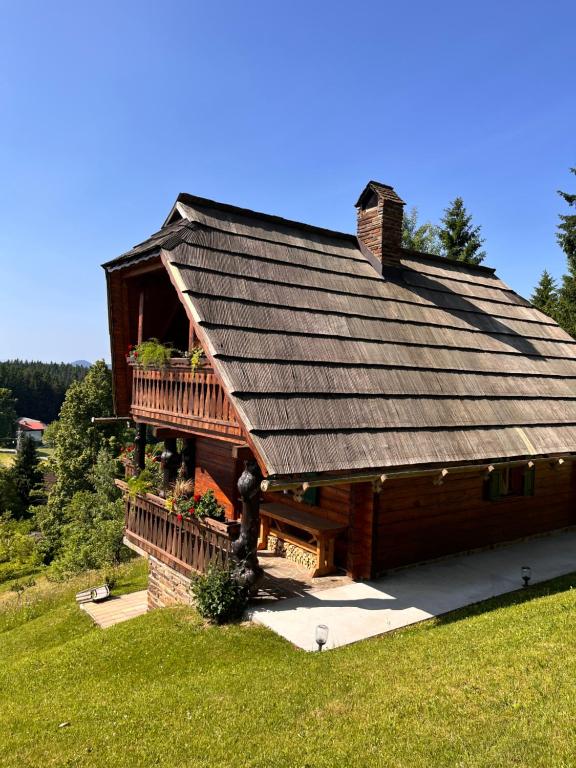 a log cabin with a large roof and a balcony at HolidayHouse Mahova koča in Zreče