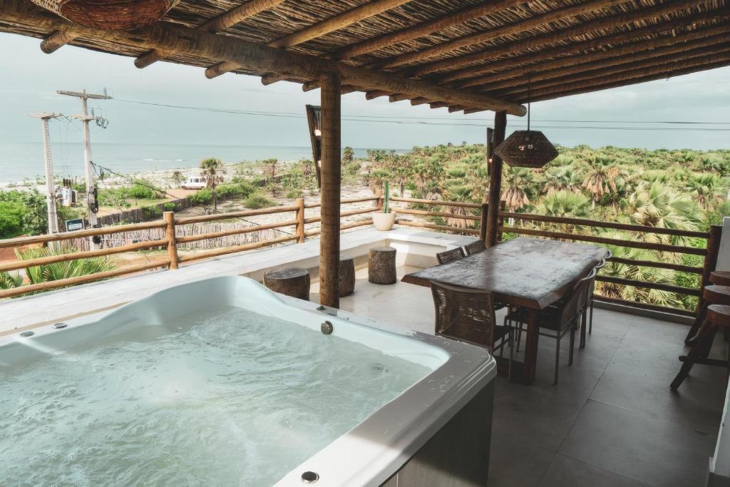 a bath tub on a balcony with a table at Casa Mandala - Rooftop com Jacuzzi e Vista Mar in Barra Grande