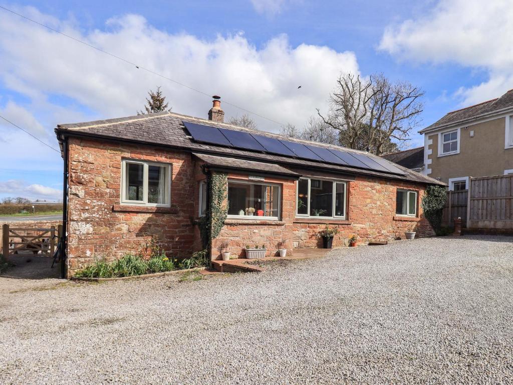 a brick house with solar panels on the roof at Yew Tree Cottage in Wigton