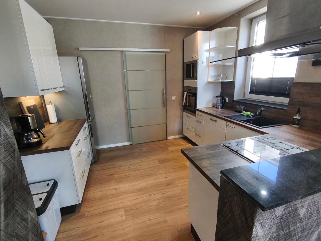 a large kitchen with white appliances and wooden floors at Hehlentor Fachwerkwohnung in Celle