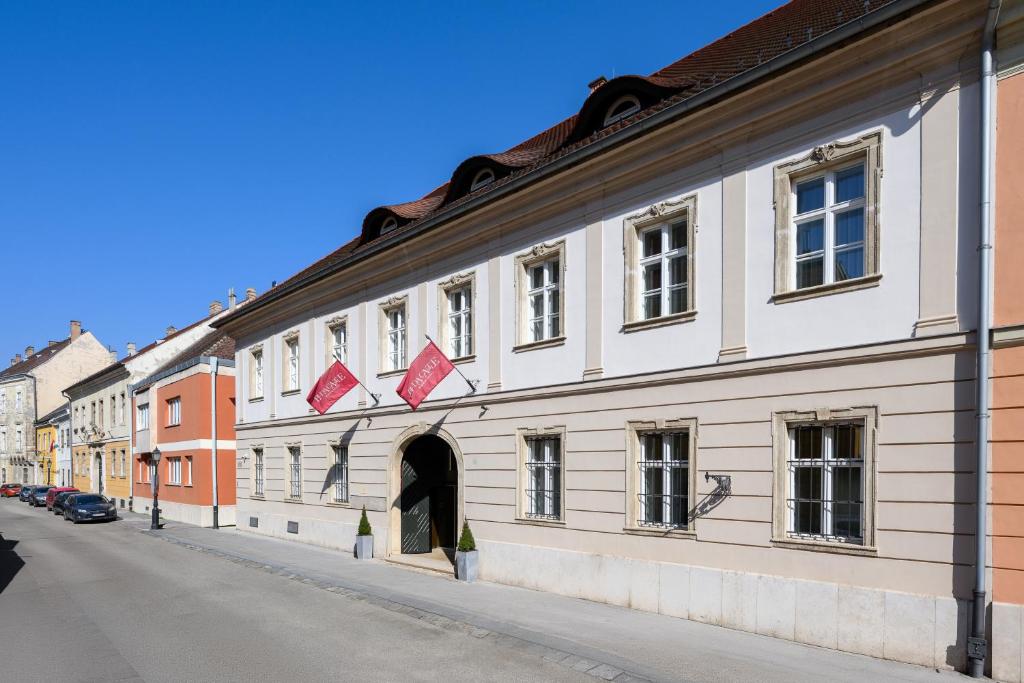 a white building with red kites on a street at Buda Castle Hotel Budapest in Budapest