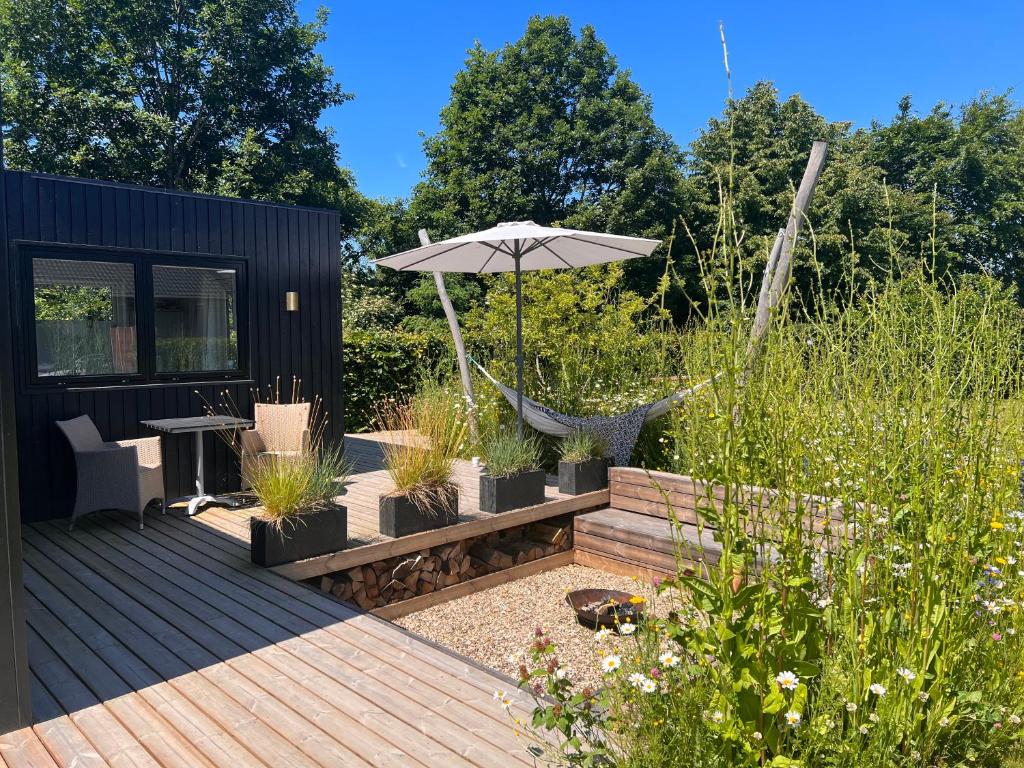a deck with an umbrella and a chair and a table at Cosy guesthouse in peaceful garden surroundings in Silkeborg