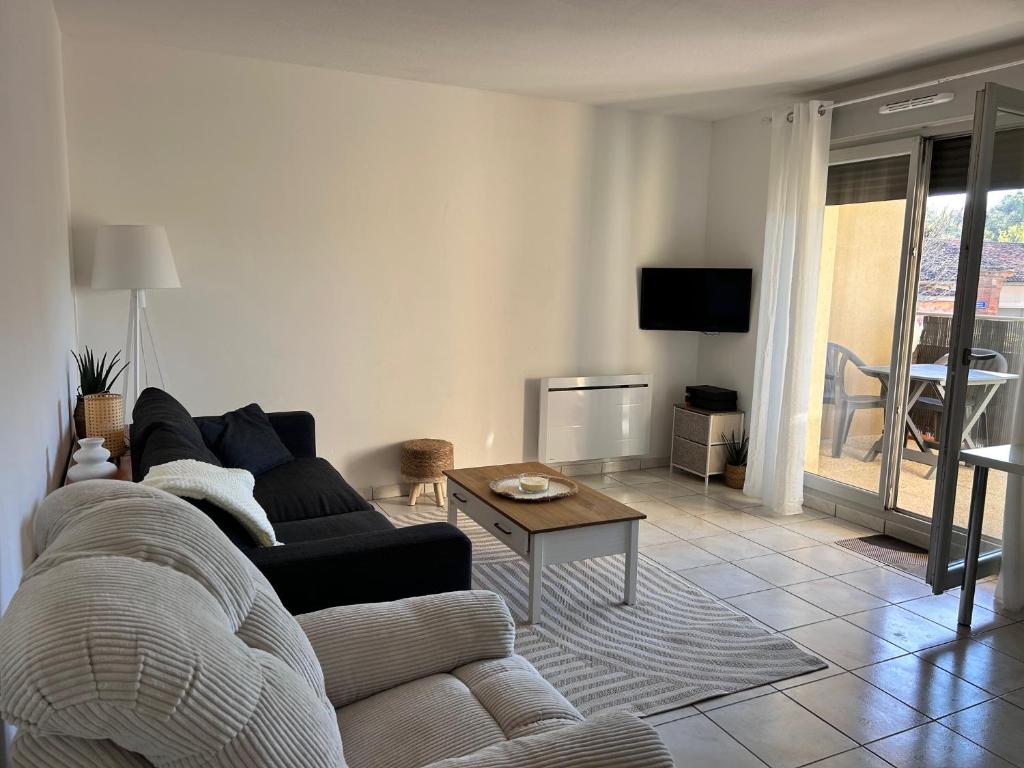 a living room with a couch and a table at T2 POMPERTUZAT Calme avec parking in Pompertuzat