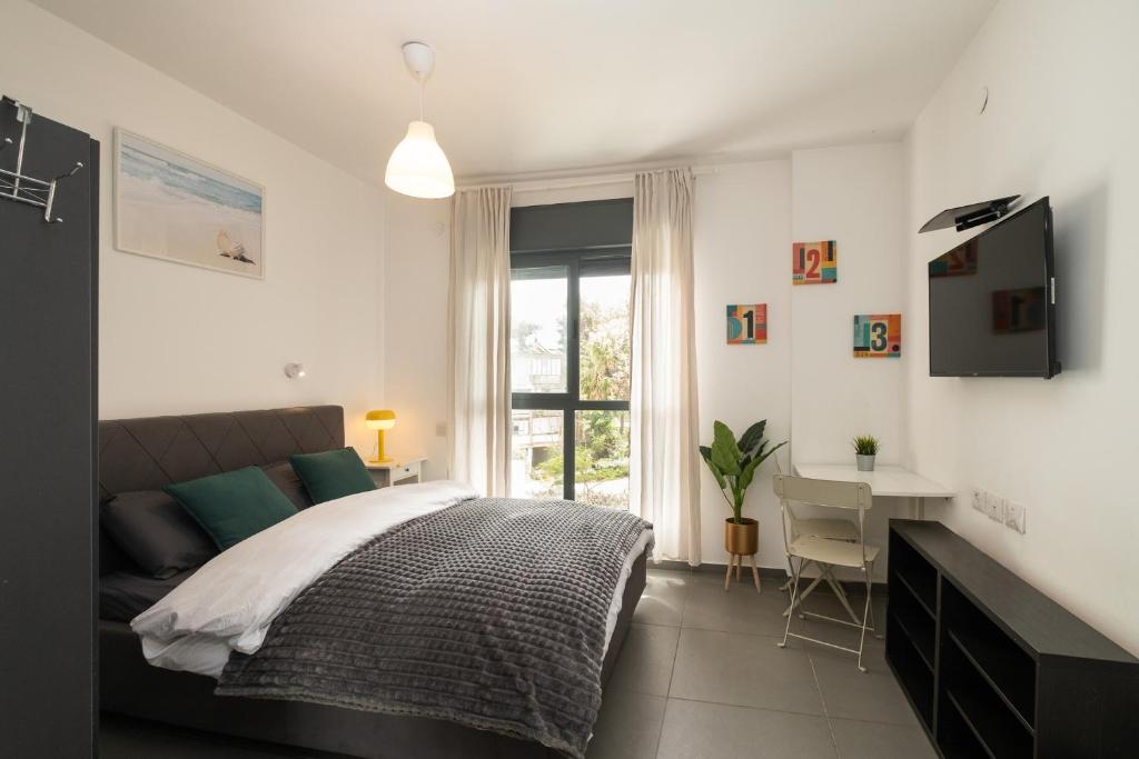 a bedroom with a bed and a desk and a window at Assuta studio in Tel Aviv