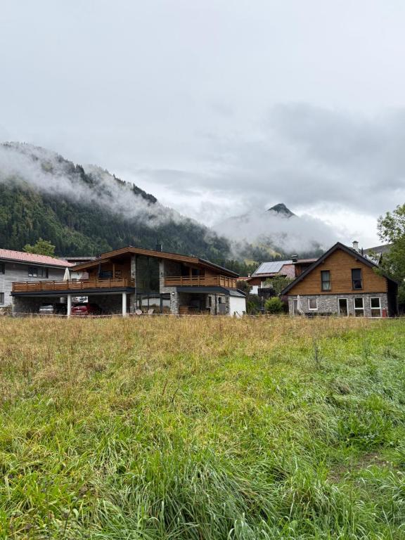 Eine Gruppe von Häusern auf einem Feld mit Bergen im Hintergrund in der Unterkunft Alprocks Alvaresort in Bichlbach