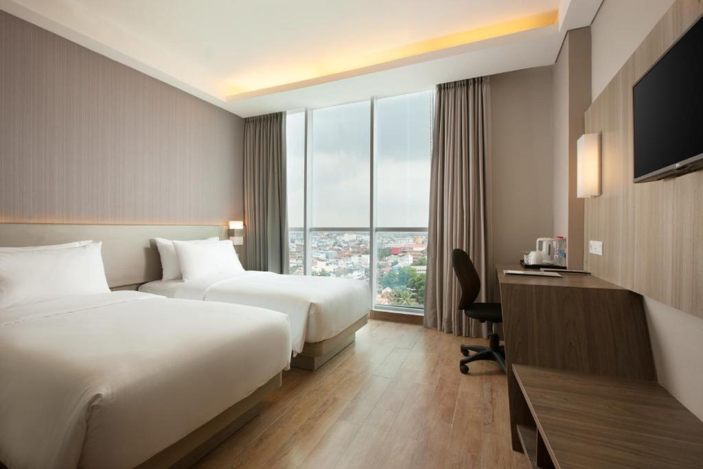 Postel nebo postele na pokoji v ubytování Hotel Santika Radial Palembang