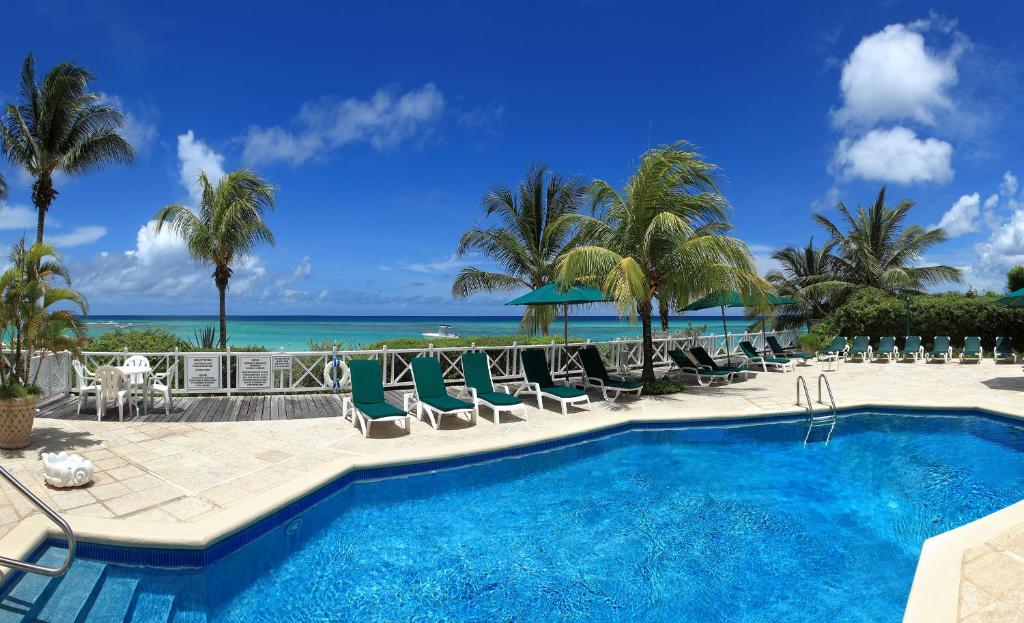 a swimming pool with chairs and the ocean in the background at Coral Sands Beach Resort in Bridgetown