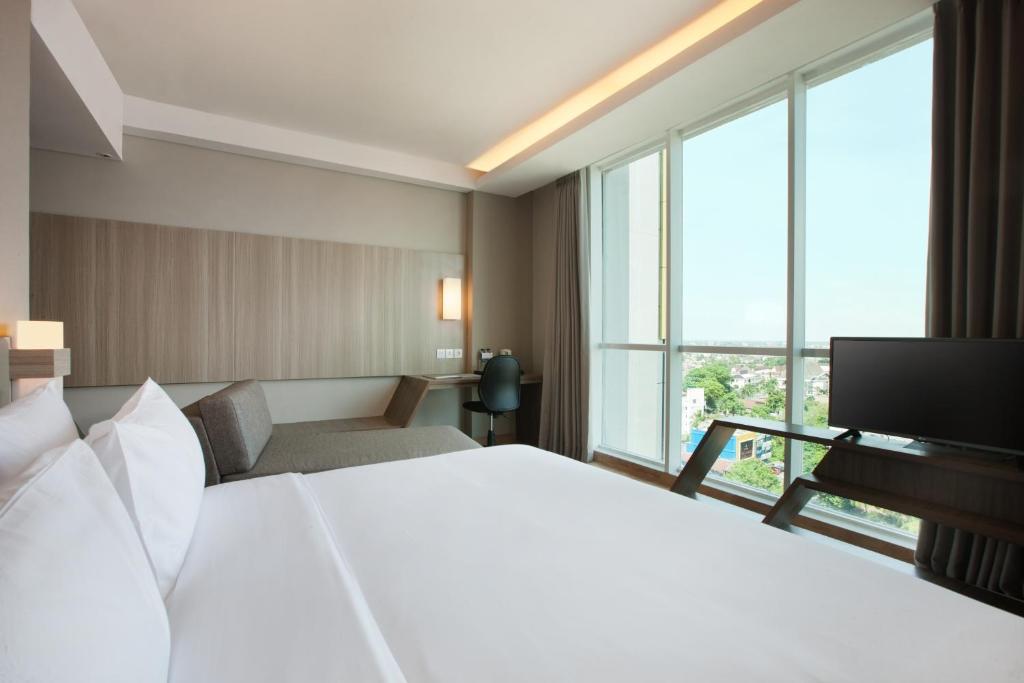 Postel nebo postele na pokoji v ubytování Hotel Santika Radial Palembang