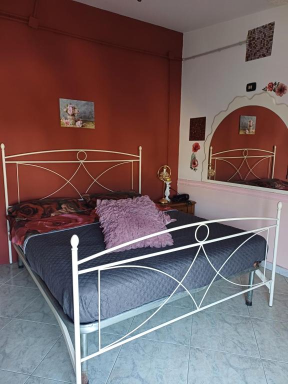 a bed in a bedroom with a red wall at B&b Cleopatra in Scalea