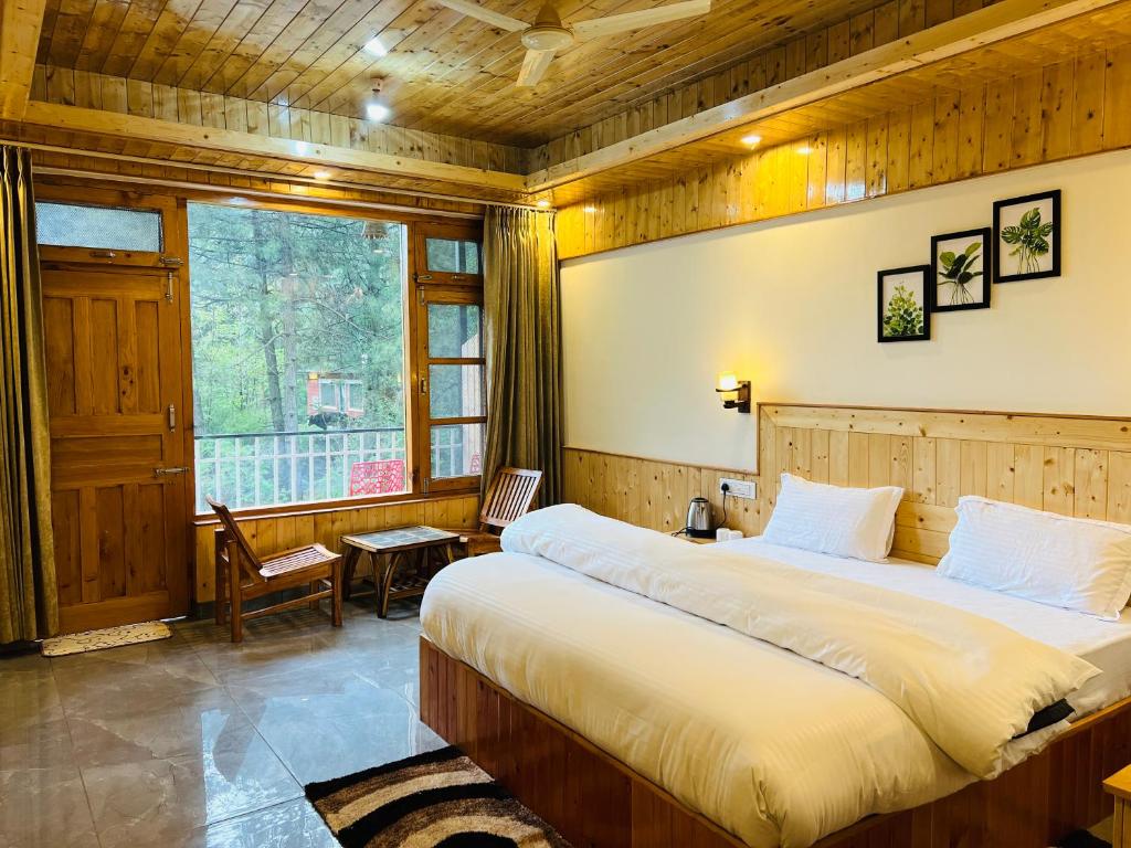 a bedroom with a large bed and a window at Tirthan Villa Homestay in Banjār