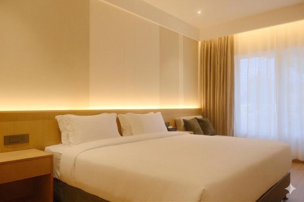 a bedroom with a large white bed and a window at Metta Shaanti Hotel Shravasti in Khargupur