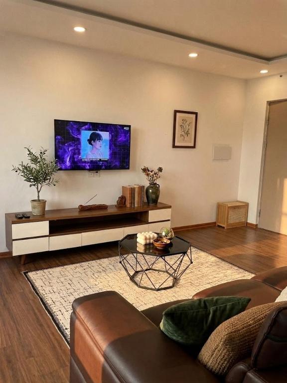 a living room with a couch and a tv on the wall at VEC Homes - Triển lãm VEC Đông Anh - 2 Phòng ngủ view sông Hồng in Dong Anh