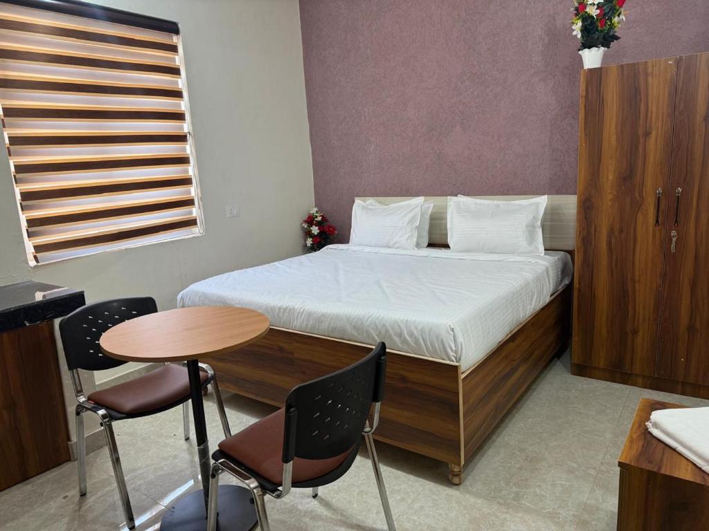 a bedroom with a bed and a table and chairs at JMD Zoom Plaza Hotel in Farrukhnagar