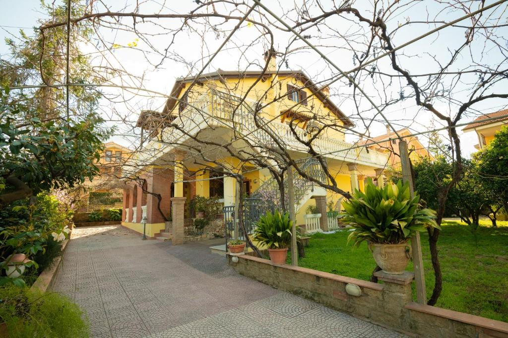a large yellow house with plants in a yard at Mary s House Cerveteri Wifi AC in Cerveteri